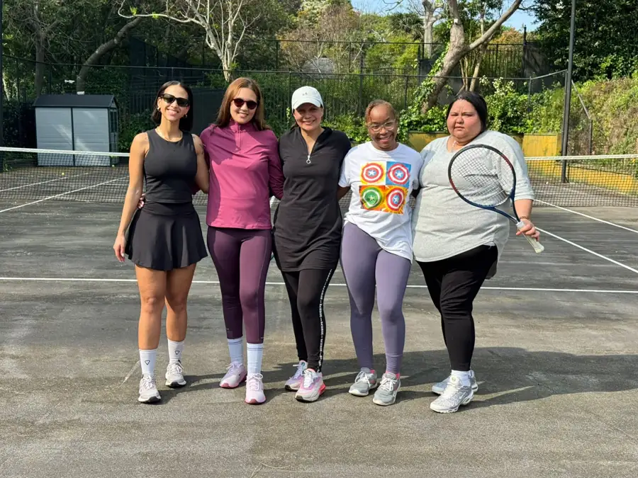 Five women of Grace & Glow standing arm in arm on a tennis court